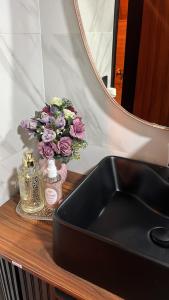 a sink and a mirror and flowers on a counter at Chalé Sol Nascente - Vista espetacular próximo as melhores praias de Floripa in Florianópolis