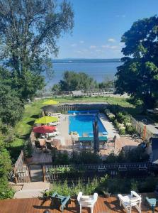 a swimming pool with chairs and umbrellas next to the water at La maison de l'île d'Orléans - B&B - déjeuner gastronomique in Saint-Jean