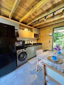 a kitchen with a washing machine and a table at Chalé Sol Nascente - Vista espetacular próximo as melhores praias de Floripa in Florianópolis