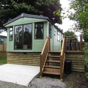 a green tiny house with a staircase and a deck at Barnkirk Holidays in Newton Stewart