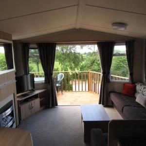 a living room with a couch and a wooden deck at Barnkirk Holidays in Newton Stewart