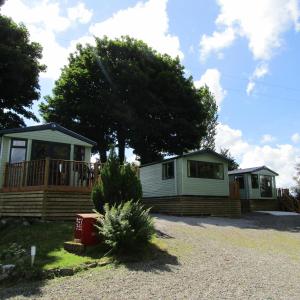 two small cottages in a parking lot with a house at Barnkirk Holidays in Newton Stewart
