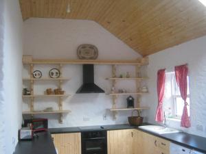 a kitchen with a stove and a sink and shelves at Rural Donegal cottage near sandy beaches in Clonmany +2 photos
