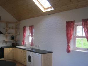 a kitchen with a washing machine and a window at Rural Donegal cottage near sandy beaches in Clonmany
