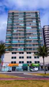 a tall building with palm trees in front of it at Frente mar na praia de Itaparica! in Vila Velha