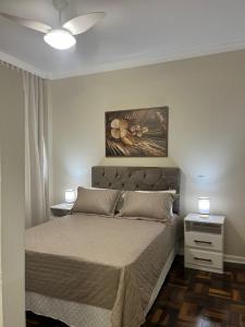 a bedroom with a bed and a painting on the wall at B-54-Central com Wi-Fi e Ventilador, Sem Garagem in Londrina