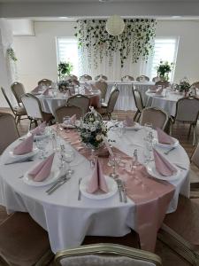 a room with tables and chairs with pink napkins at Ezüst Mező Vendégház in Nagyecsed