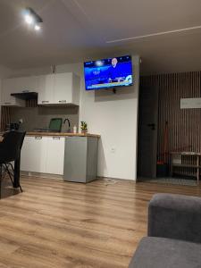 a living room with a kitchen and a tv on the wall at Zacisze nad wodą in Strzegocice