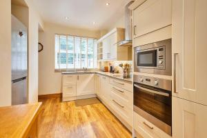 a kitchen with white cabinets and a sink and a microwave at Host & Stay - The Station Cottage in Stanley +15 photos