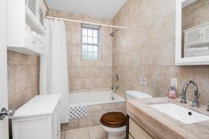 a bathroom with a tub and a toilet and a sink at Cozy cottage close to NYC in Yonkers +1 photo