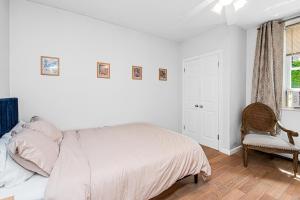 a white bedroom with a bed and a chair at Cozy cottage close to NYC in Yonkers