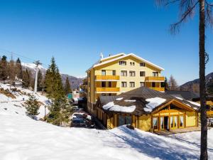 un grand bâtiment jaune avec de la neige devant lui dans l'établissement Park Hotel, à Folgarida