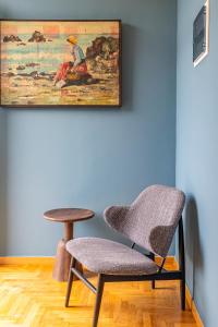 a chair and stool next to a wall with a painting at Iliotropio Athens, Thisio in Athens