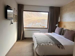 a bedroom with a bed and a large window at Lodge El Morado in Refugio Lo Valdés