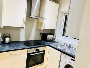 a small kitchen with a sink and a stove at Small 3 Bed Flat near Heathrow in Staines
