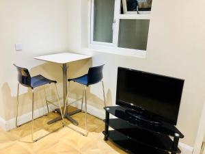 a living room with a table and two chairs and a television at Small 3 Bed Flat near Heathrow in Staines
