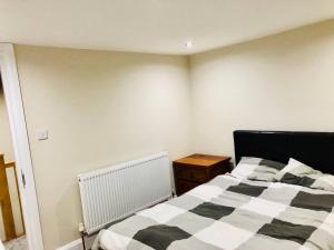 a bedroom with a black and white bed and a wooden table at Small 3 Bed Flat near Heathrow in Staines