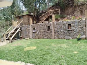 a stone wall with a staircase and a building at Hatun Apu Center Casa de Ayahuasca y San Pedro in Pisac