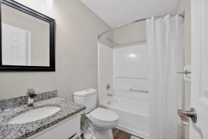 a bathroom with a toilet and a sink and a shower at Stylish 2BR2BA with room to unwind in Stockbridge +12 photos