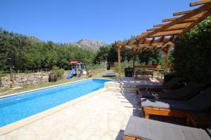 a backyard with a swimming pool with a wooden pergola at Oak House in Zadvarje