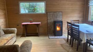 a living room with a fireplace and a table and a couch at Cabañas lugar de Refugio in Queilén