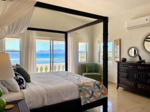 a bedroom with a bed with a view of the ocean at Lockrum Point Villa - Upscale Ocean Front, Pool with Gazebo in South Hill Village