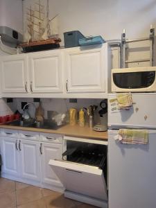 a kitchen with white cabinets and an open oven at Le refuge de la Fée - centre et plage in Fouras
