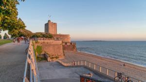 a view of a beach with a castle and the ocean at Le refuge de la Fée - centre et plage in Fouras