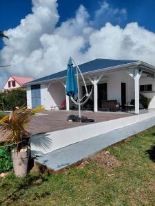 a house with a porch with a blue umbrella at Villa de charmes in Capesterre
