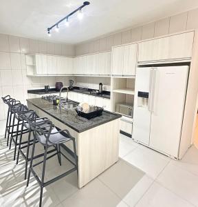 a kitchen with a refrigerator and a table and chairs at Casa espaçosa com piscina, a 2 quadras do mar! in Guaratuba