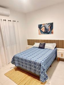 a bedroom with a bed with a blue and white blanket at Casa espaçosa com piscina, a 2 quadras do mar! in Guaratuba +20 photos