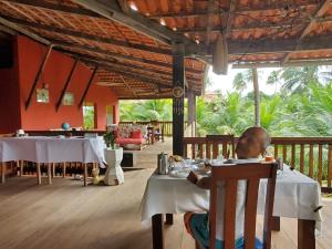 Ein Mann sitzt an einem Tisch in einem Restaurant in der Unterkunft Ecolodge Batel Alagoas in Coruripe