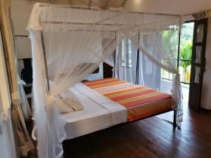 a bed with a canopy in a room with a window at Pilgrims Nature Villa in Ahangama