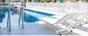 a row of white chairs next to a swimming pool at HOTEL SETTIBI 20m dalla spiaggia in Giulianova