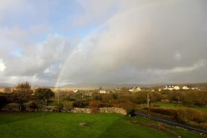 a rainbow in the sky over a green field at Connemara luxury log out in Camus Eighter