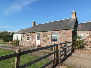an old stone cottage with a wooden fence at The Bothy in Blairgowrie