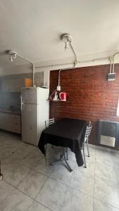 a kitchen with a black table with chairs and a refrigerator at Maximina Home in Comodoro Rivadavia +6 photos