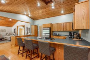 a kitchen with wooden cabinets and a bar with chairs at Cottage On The Cove by Railey Vacations in Swanton