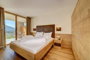 a bedroom with a large bed and a large window at Panorama Residence Öhlerhof in Lagundo +20 photos