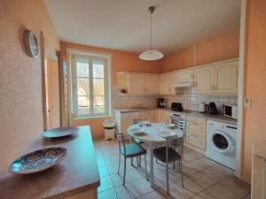 a kitchen with a table and chairs in a kitchen at Les Capucins - Élégance au Cœur de Remiremont in Remiremont