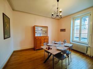 a dining room with a wooden table and chairs at Les Capucins - Élégance au Cœur de Remiremont in Remiremont