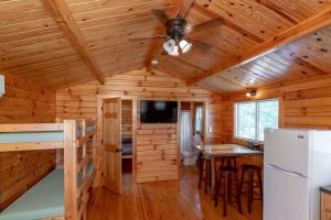 a log cabin kitchen with a refrigerator and a tv at Sun Outdoors Association Island in Henderson Harbor