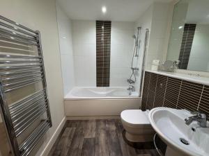a bathroom with a tub and a toilet and a sink at Three bed apartment in the Tower in Swansea +14 photos