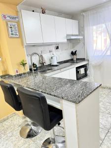 a kitchen with white cabinets and a granite counter top at Fortuna Apart in General Roca +2 photos