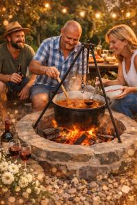a group of people sitting around a pot over a fire at Furó Vendégház in Fülöp