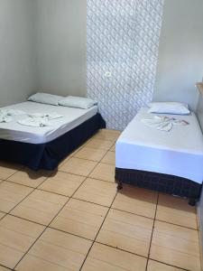 two beds in a room with a wooden floor at Pousada Costa Brasil Engenheiro Beltrao in Engenheiro Beltrão