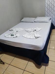 a bed with white sheets and napkins on it at Pousada Costa Brasil Engenheiro Beltrao in Engenheiro Beltrão