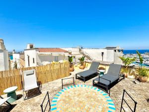 a patio with chairs and a table and the ocean at La Torretta - Authentic Historic House with Panoramic Sea-View Terrace in Otranto Old Town - Marea Stays Collection in Otranto