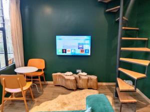 a room with a tv and a table and chairs at Lux tree house karen in Nairobi