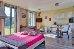 a bedroom with a bed with pink sheets and a kitchen at Villa Argonne - Cottages & Spa Privatif in Ouville-la-Rivière